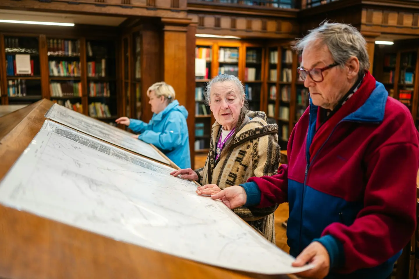 Mensen bestuderen kaarten en documenten aan een lange tafel.